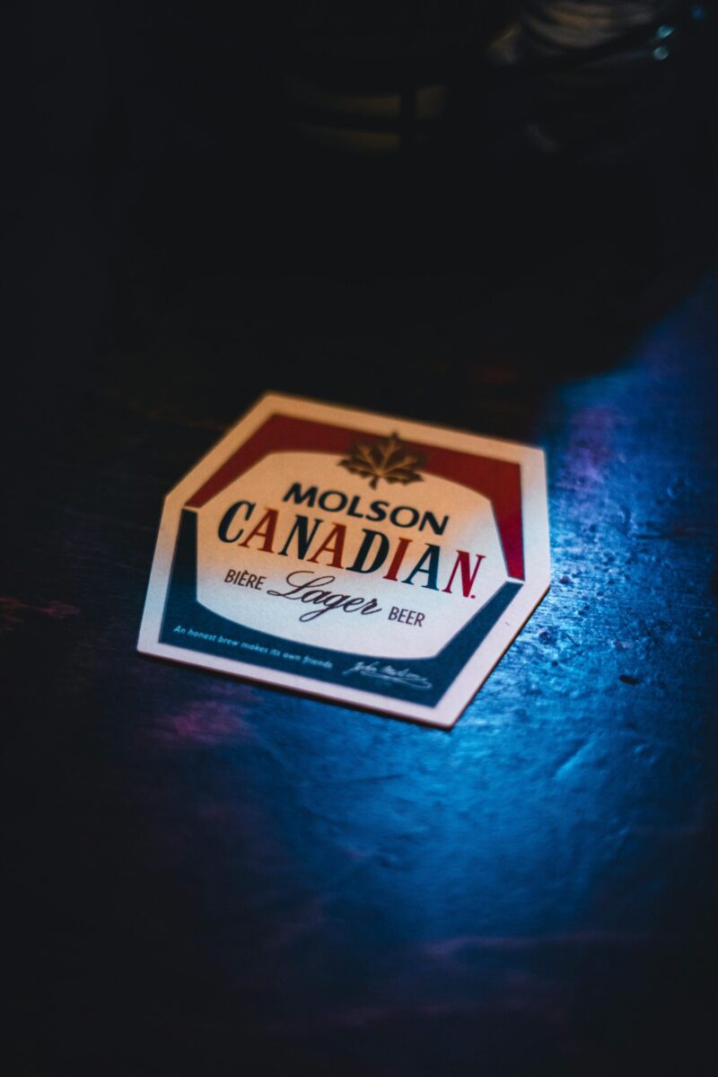 Retro Molson Canadian beer coaster with vintage aesthetic on a dark wooden surface.